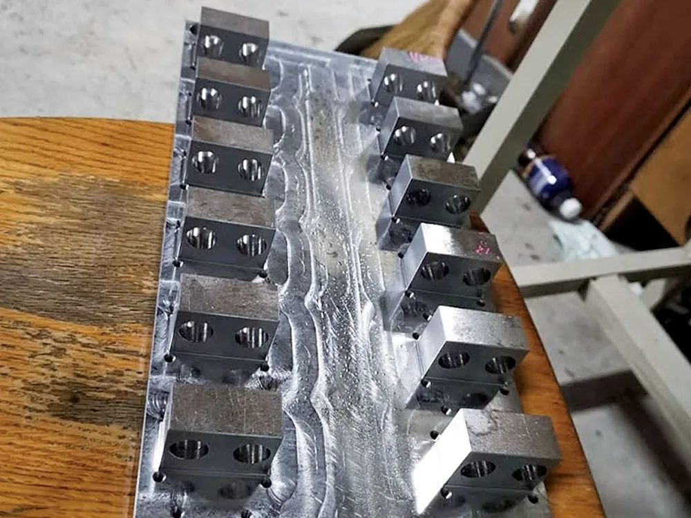 呈相加工的自動化機械設備零件：一整排鋁合金固定塊排列在長條底板上
